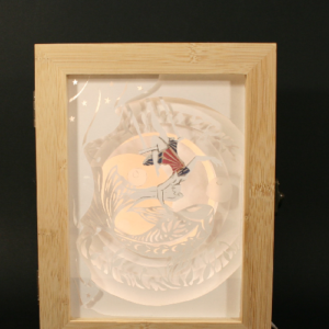 lampe artisanale en papier découpé dans boite en bambou. représente une trapeziste et une carpe . inspiration cirque et kirigami. réalisé à la main par Flavie andré