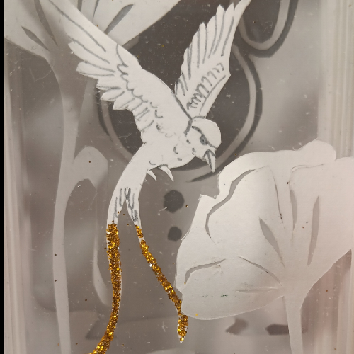 Lampe poétique en papier découpé représentant des oiseaux parmi les fleurs. détail d'un oiseau, lampe éteinte